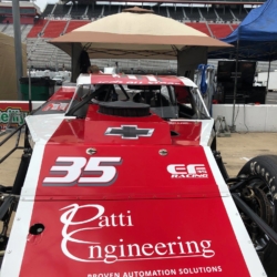 Red and white race car with number 35 and Patti Engineering logo at a racetrack under a canopy.