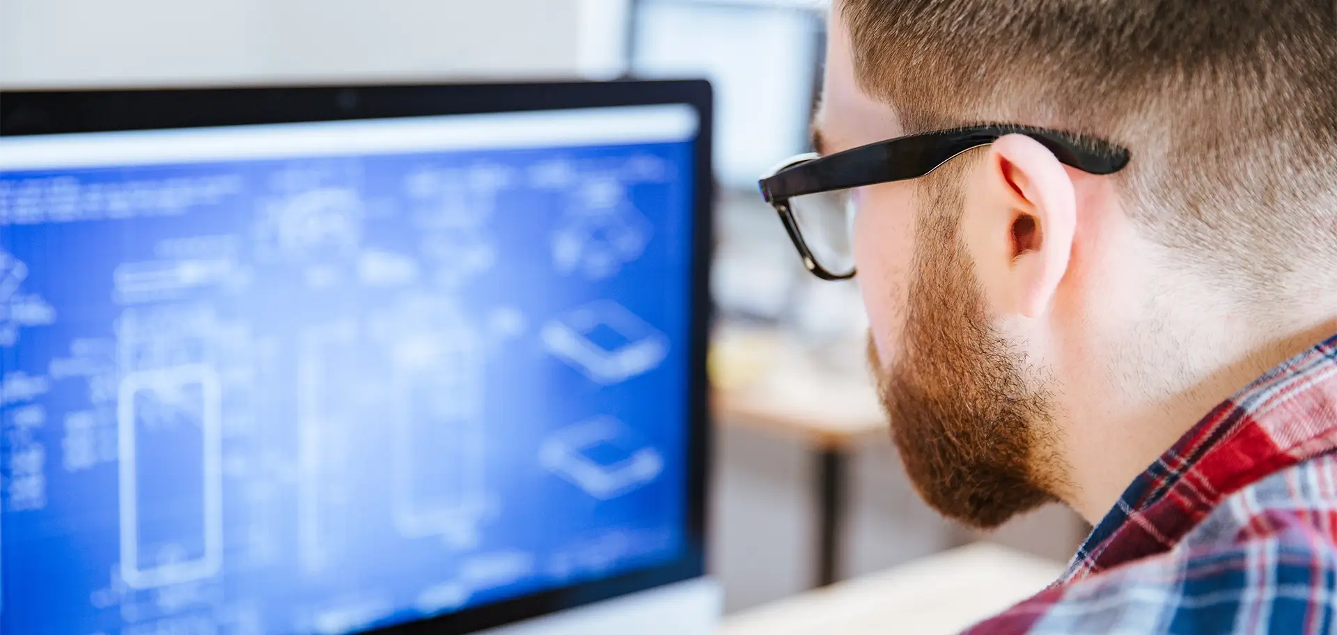 Closeup of man in glasses making blueprints on computer