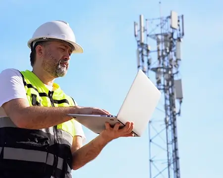 Engineer using laptop computer testing the communications tower